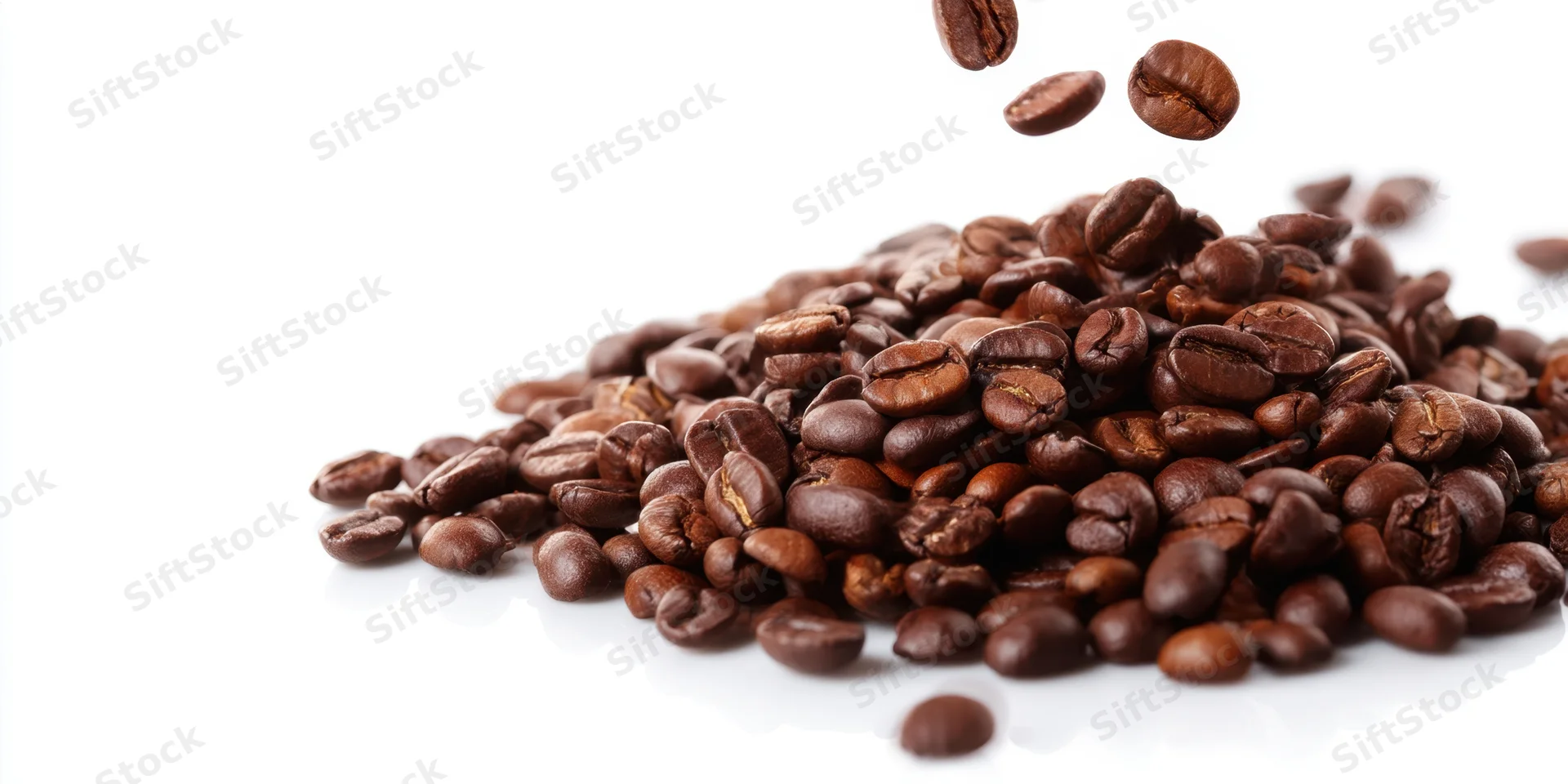 Roasted coffee beans falling onto a pile on a white background