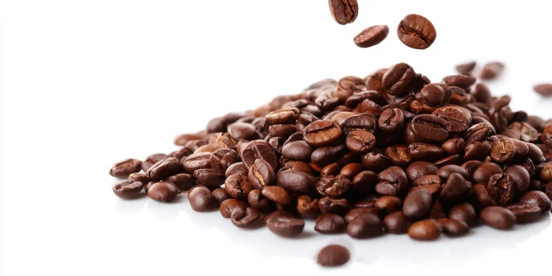 Roasted coffee beans falling onto a pile on a white background