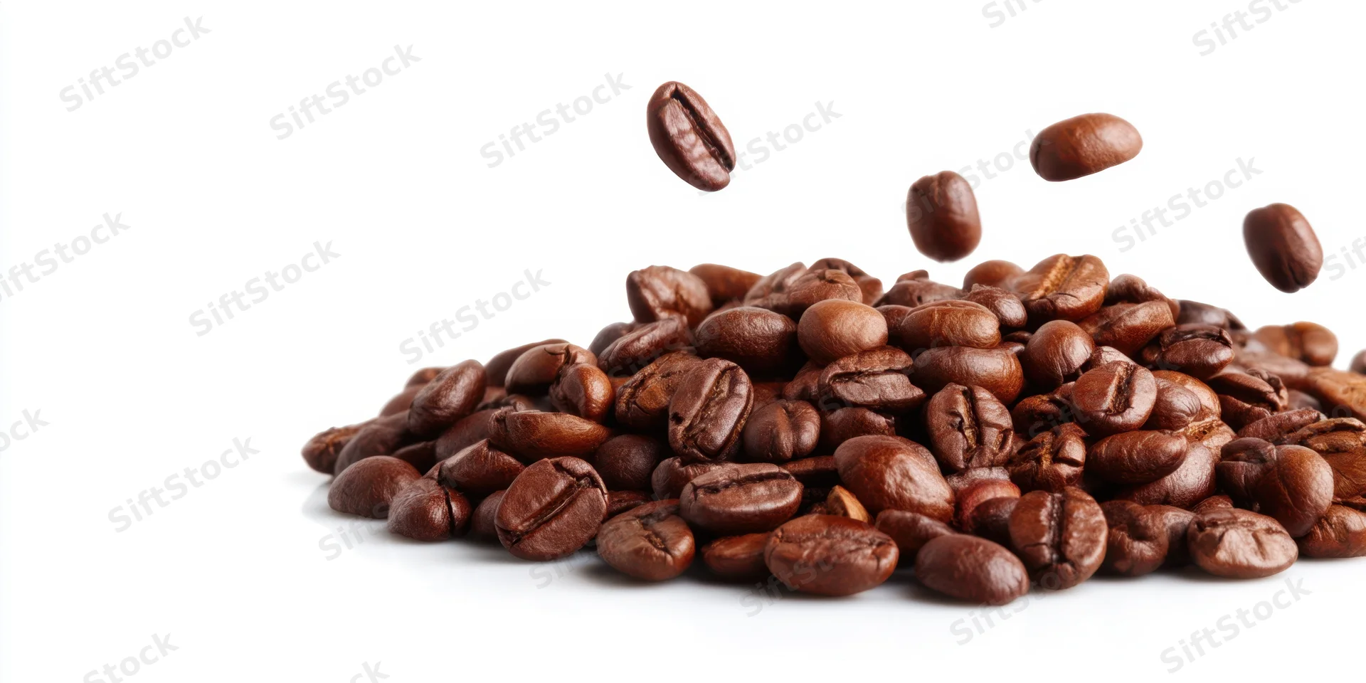 Roasted coffee beans falling onto a pile on a white background