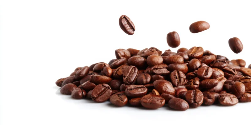 Roasted coffee beans falling onto a pile on a white background