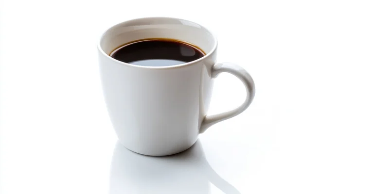 White ceramic coffee mug filled with dark coffee on a clean white surface