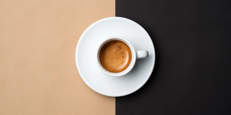 White espresso cup with crema on saucer centered on split beige and black background