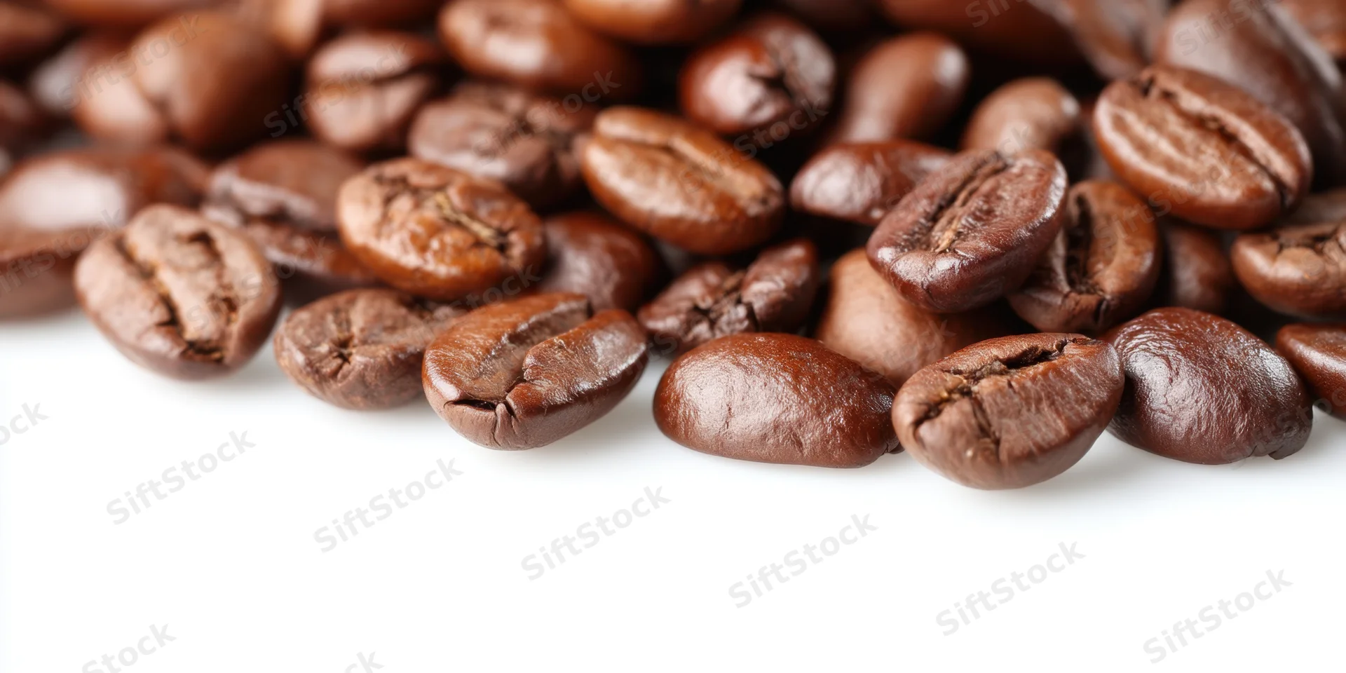Roasted coffee beans scattered across a white surface with copyspace