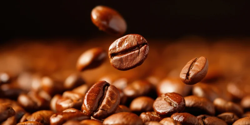Roasted coffee beans falling in midair over a pile of beans