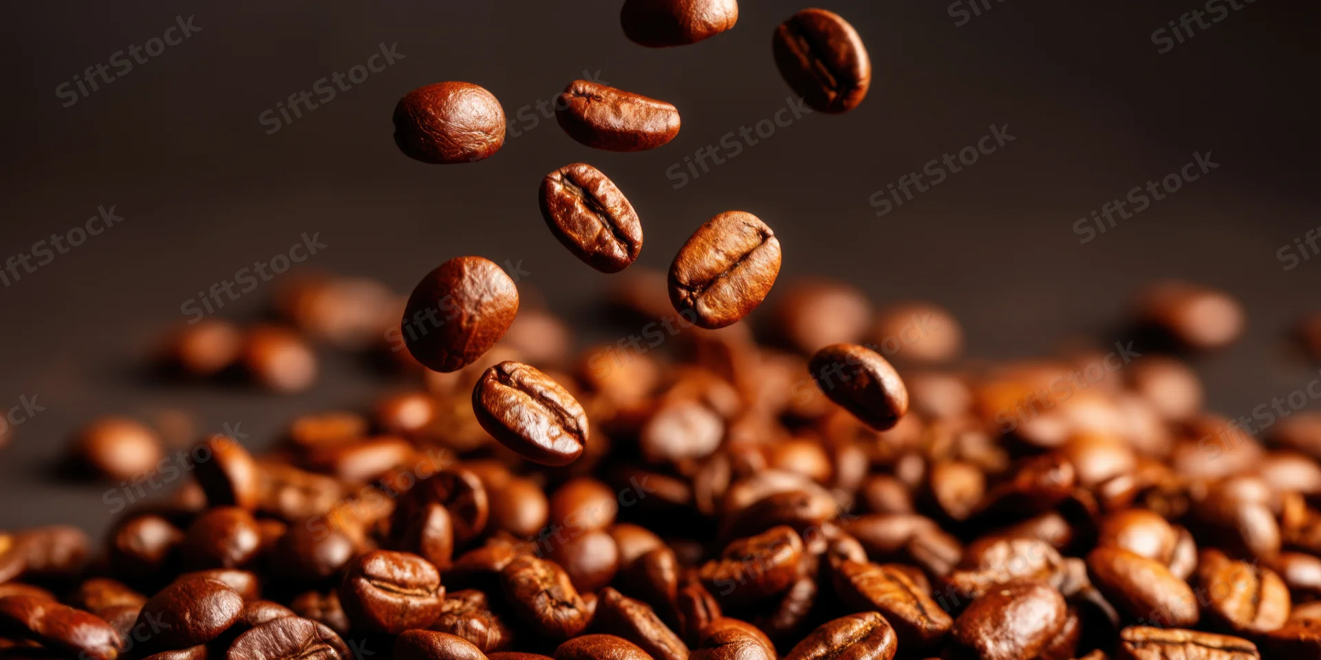 Roasted coffee beans falling in midair over a pile on dark surface