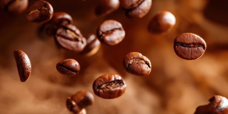 Roasted coffee beans floating in warm smoke with shallow focus and brown tones