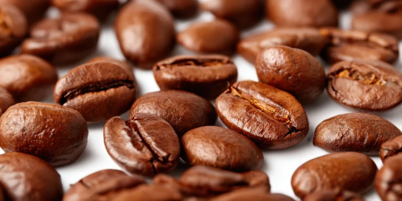 Roasted coffee beans scattered on a white background in closeup view
