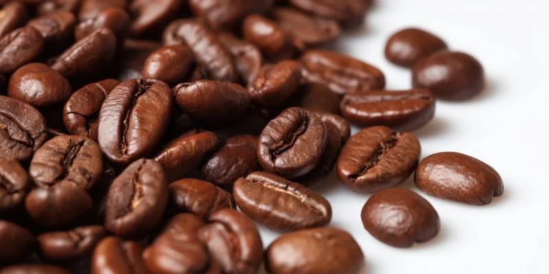 Roasted coffee beans scattered on a white background