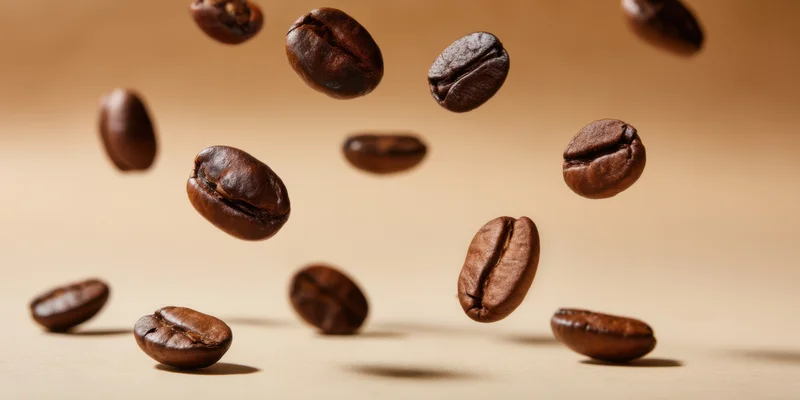 Roasted coffee beans floating in midair above a warm beige surface