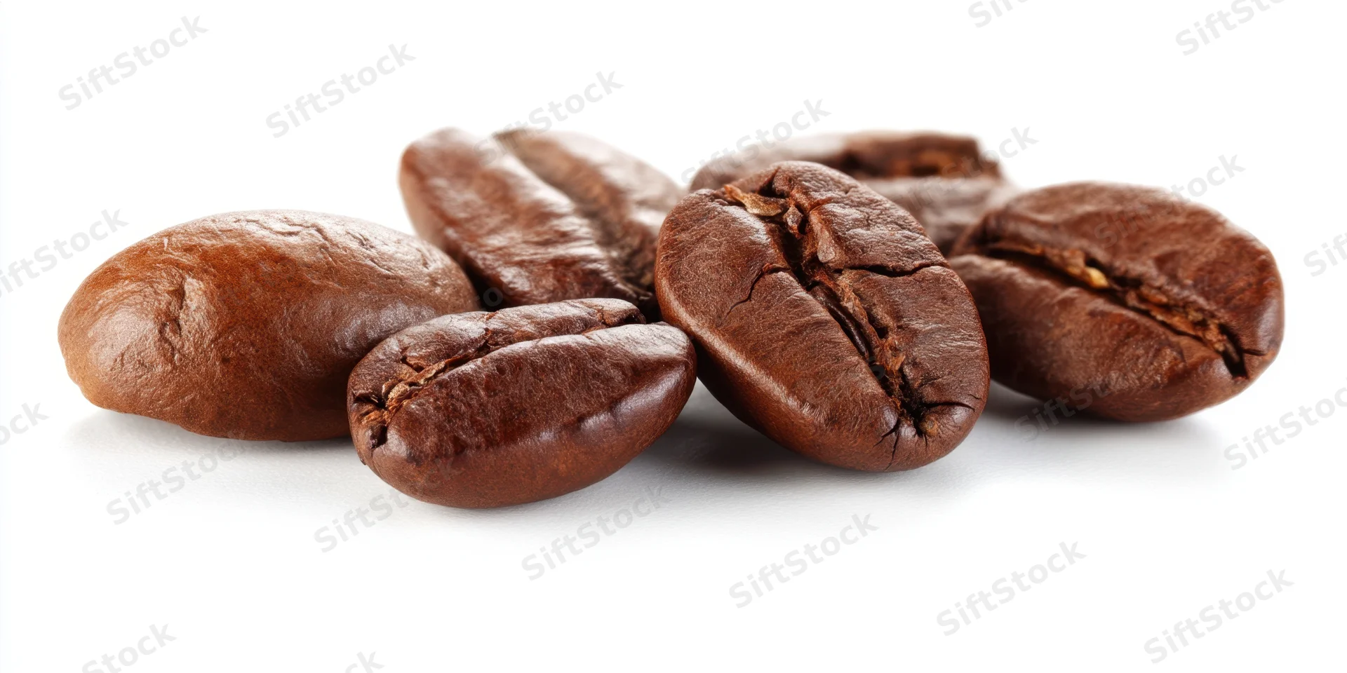 Closeup of six roasted coffee beans arranged on a white surface