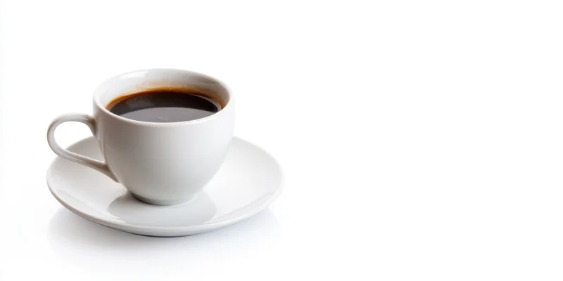 White ceramic coffee cup filled with dark coffee on matching saucer against white background