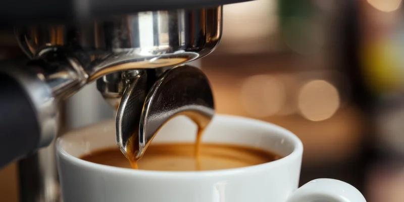 Espresso machine pouring coffee into a white cup in a cafe setting
