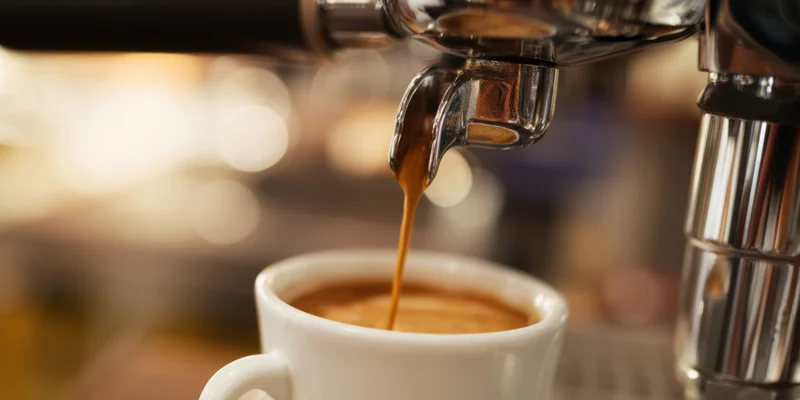 Espresso machine pouring coffee into a white cup in a cafe