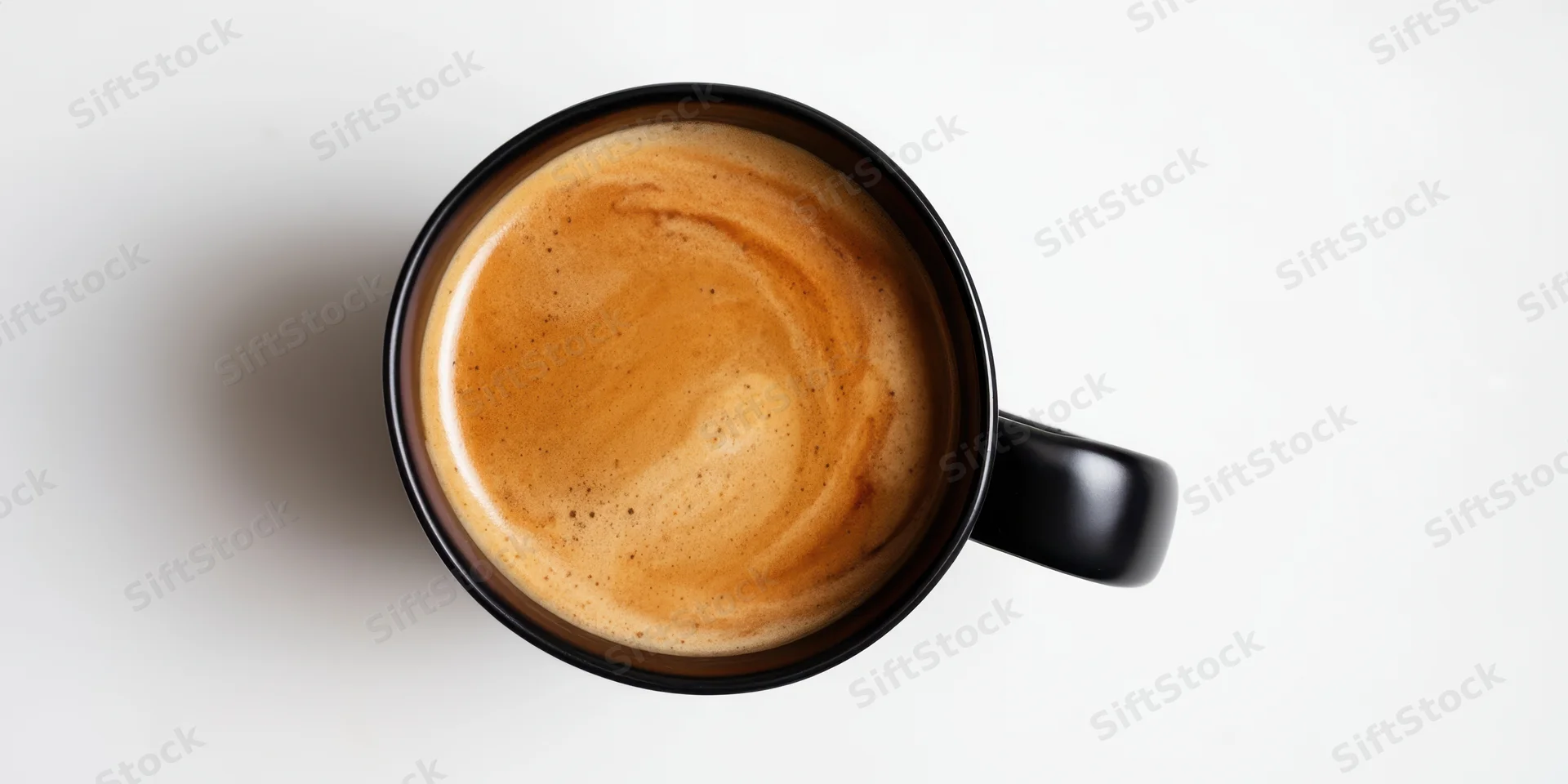 Top-down view of a black ceramic mug filled with coffee crema on a white surface