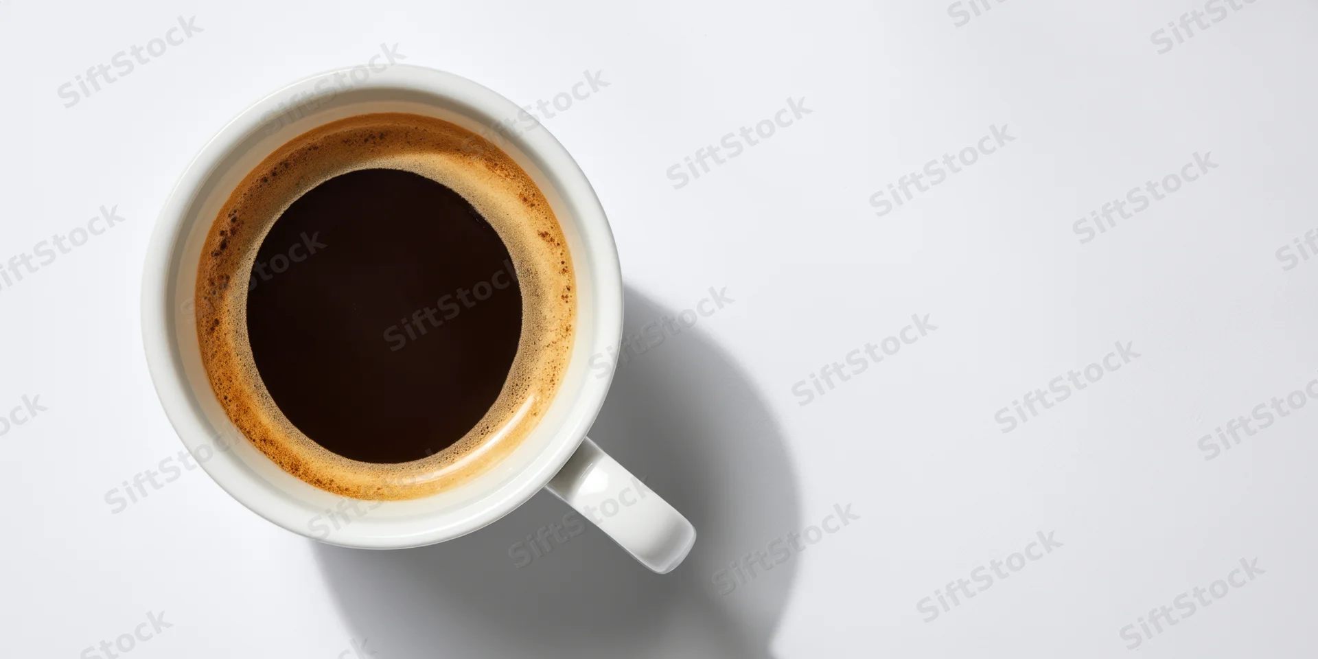 White ceramic coffee cup filled with dark coffee viewed from above on plain white surface