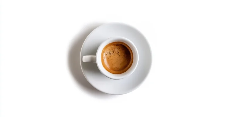 White porcelain espresso cup with rich crema on saucer against white background