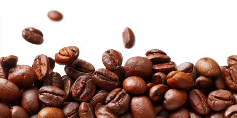 Roasted coffee beans piled along the bottom with some falling above on white background