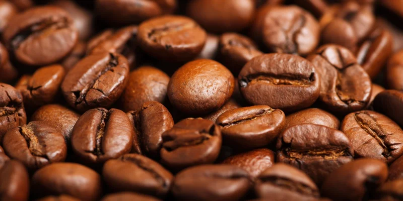 Roasted coffee beans densely scattered across the frame in closeup view