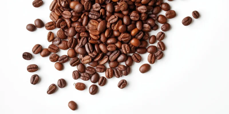 Roasted coffee beans scattered across a clean white background