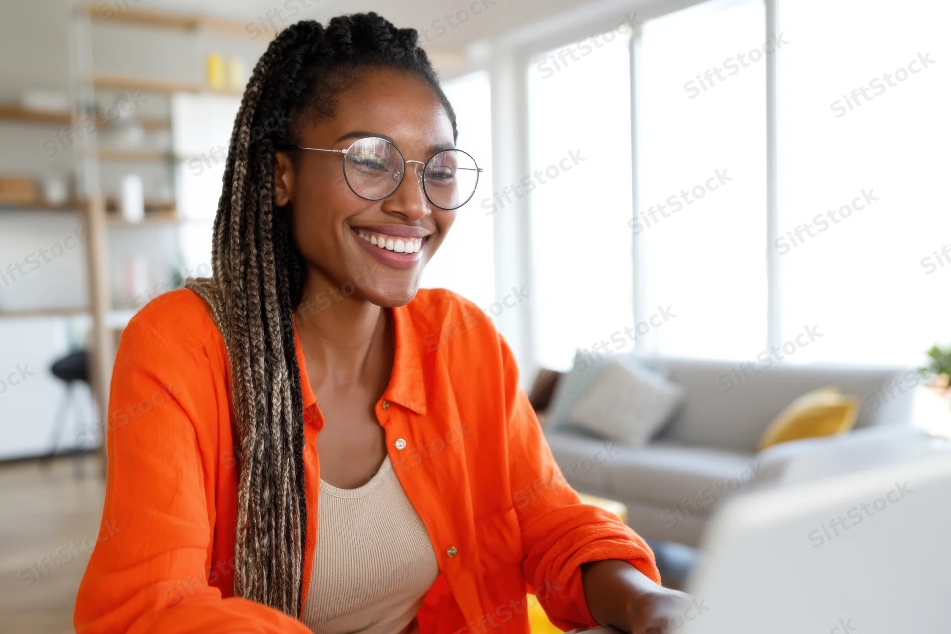 Young african woman smiling while using laptop at home