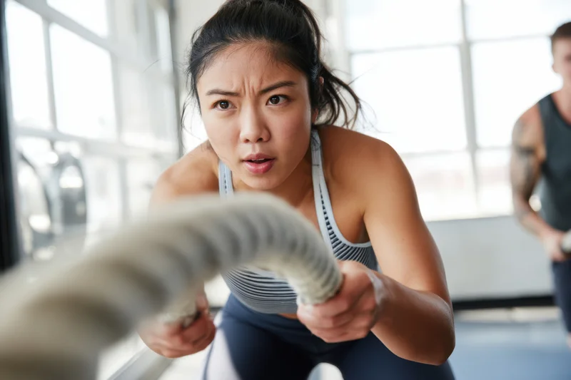 Woman using battle ropes during intense workout in gym
