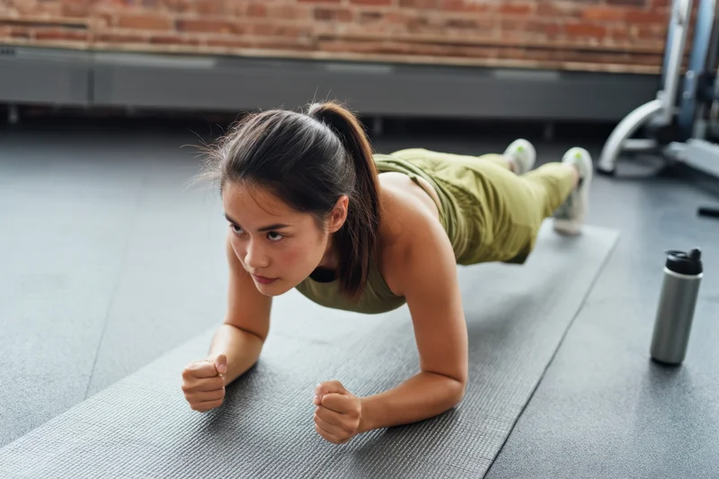 Woman doing pushup on exercise mat in gym