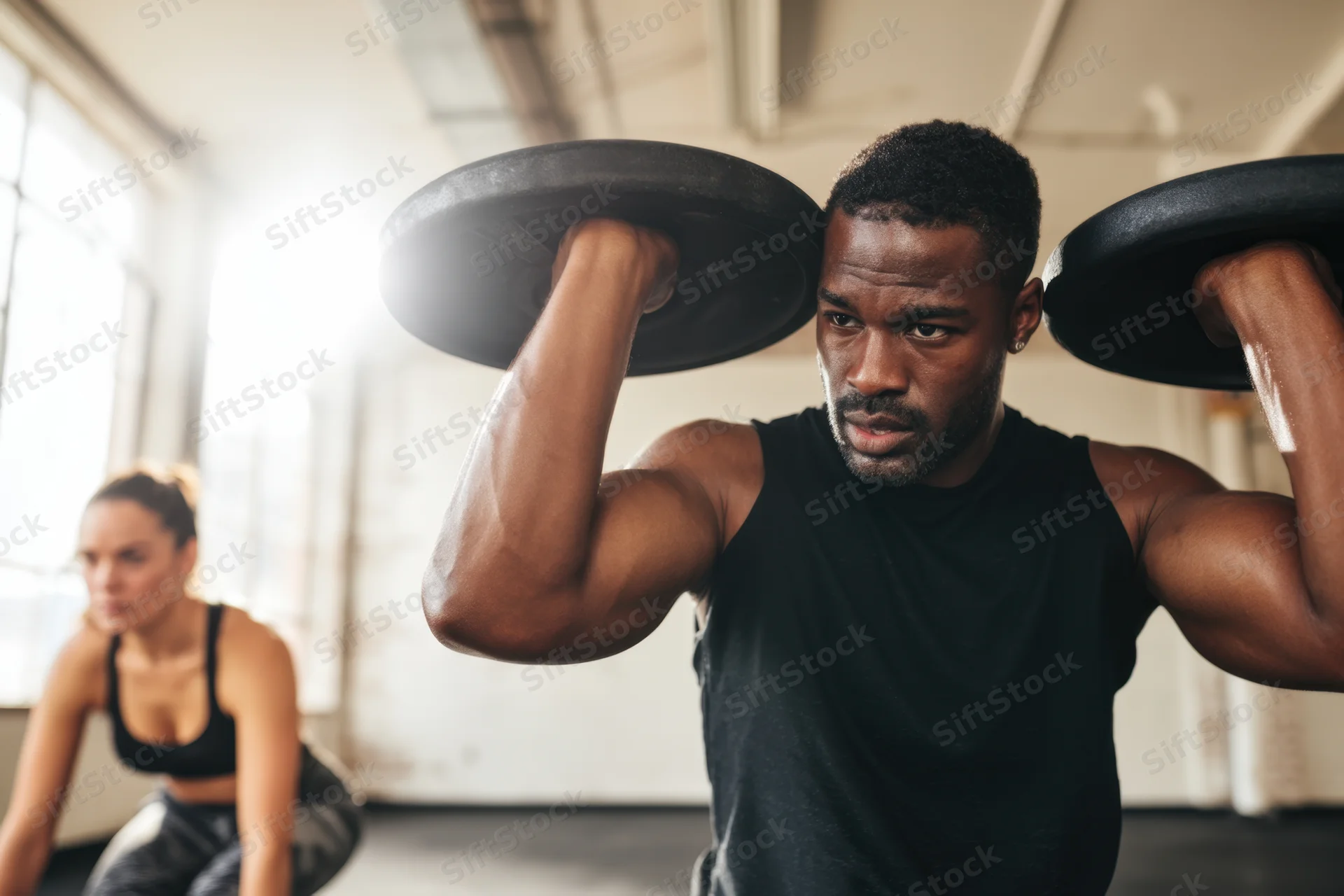 Man lifting weight plates in gym with focused expression