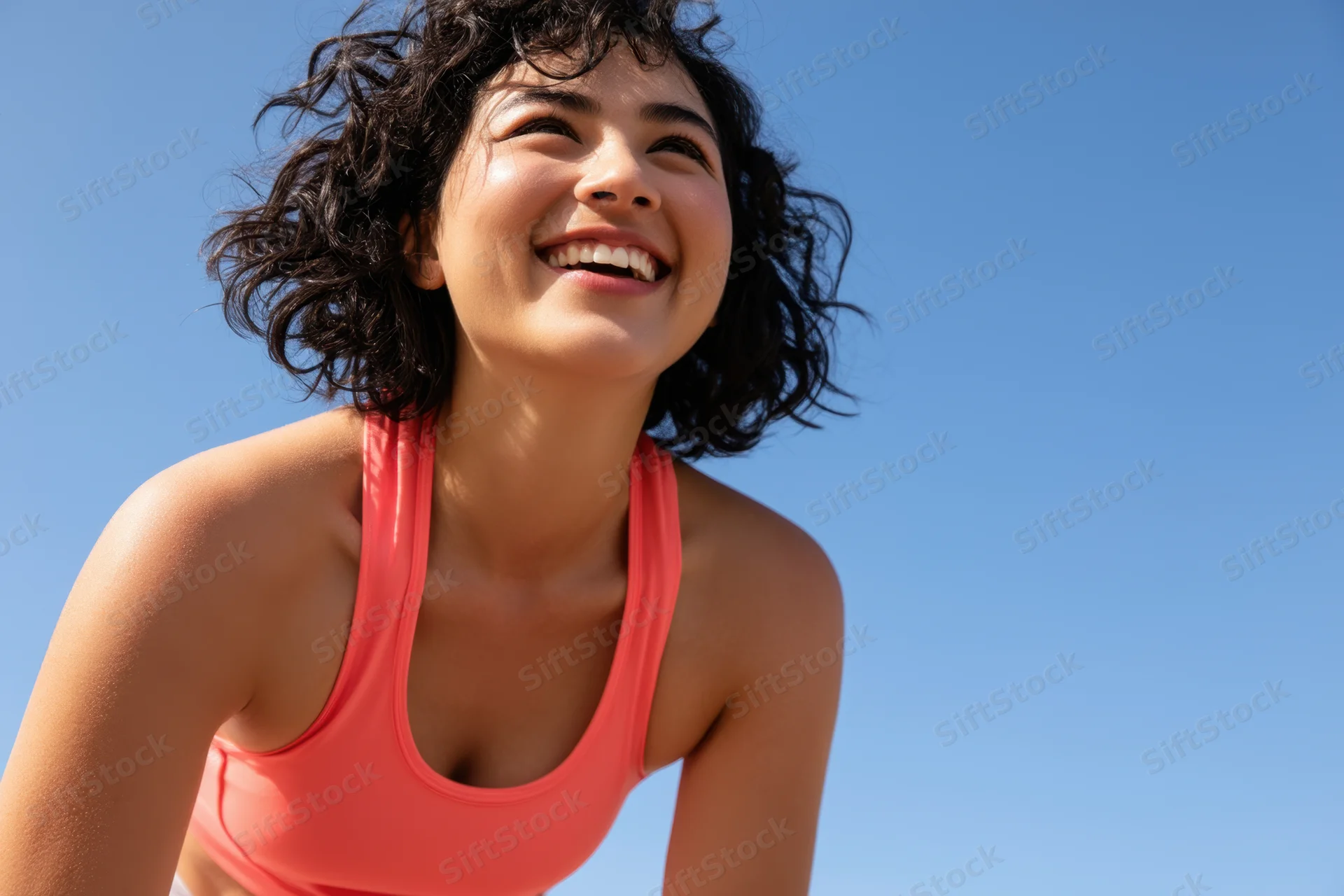 Woman smiling in coral athletic wear outdoors under blue sky