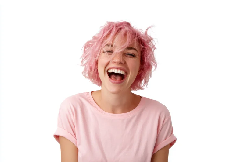 Woman with short messy pink hair laughing joyfully in a light pink t-shirt against white background