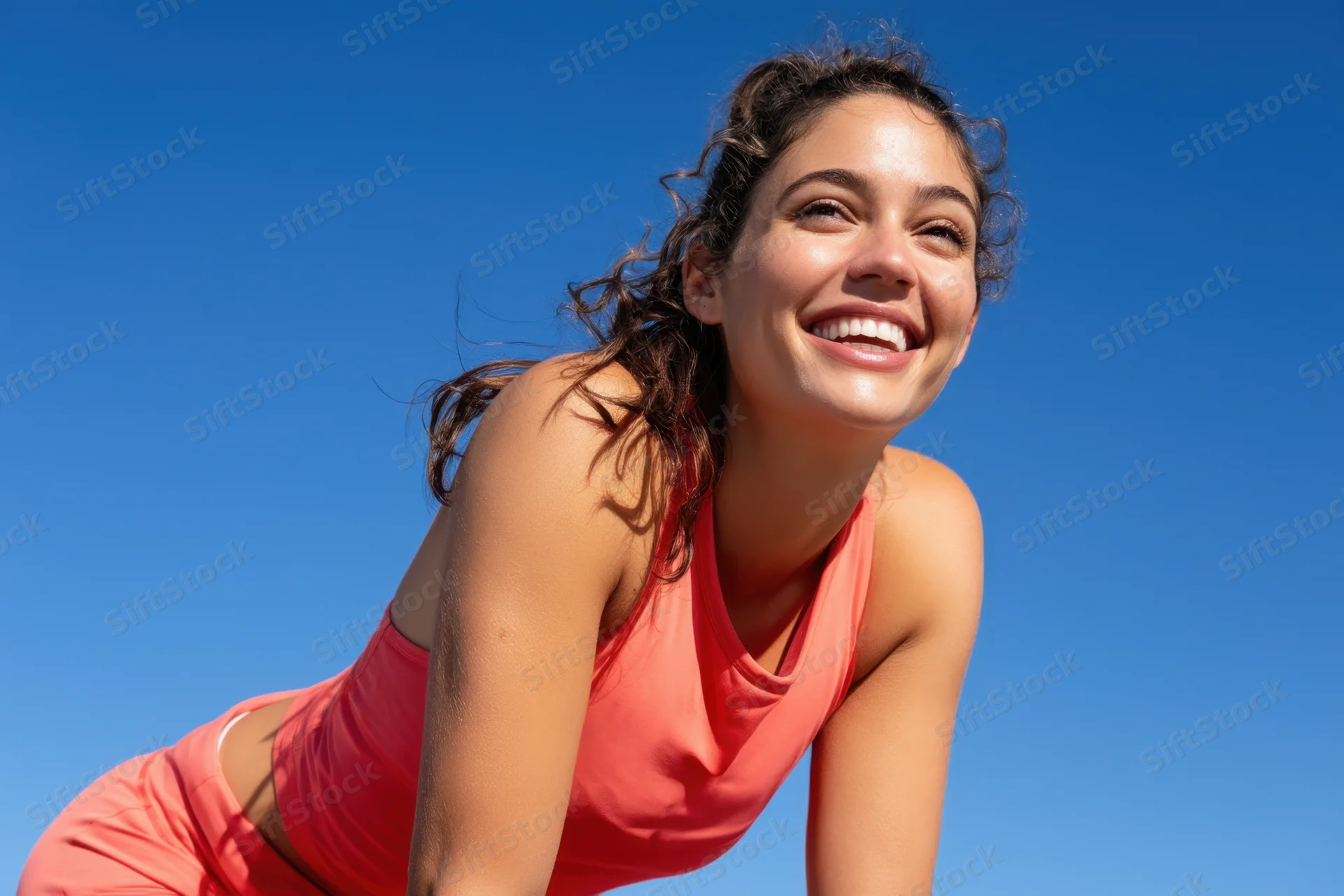 Smiling woman in coral athletic wear leaning forward outdoors