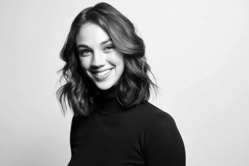 Smiling woman with shoulder-length wavy hair in black turtleneck posing in studio