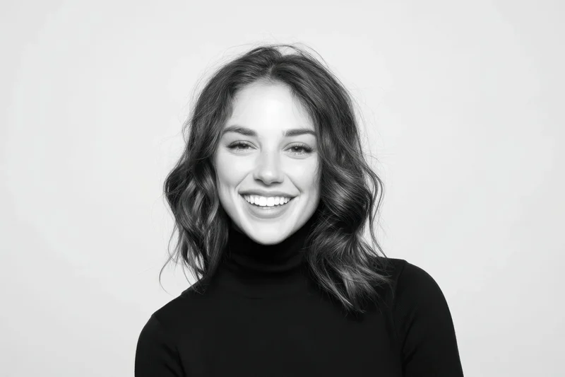 Smiling woman with shoulder-length wavy hair in black turtleneck against white background
