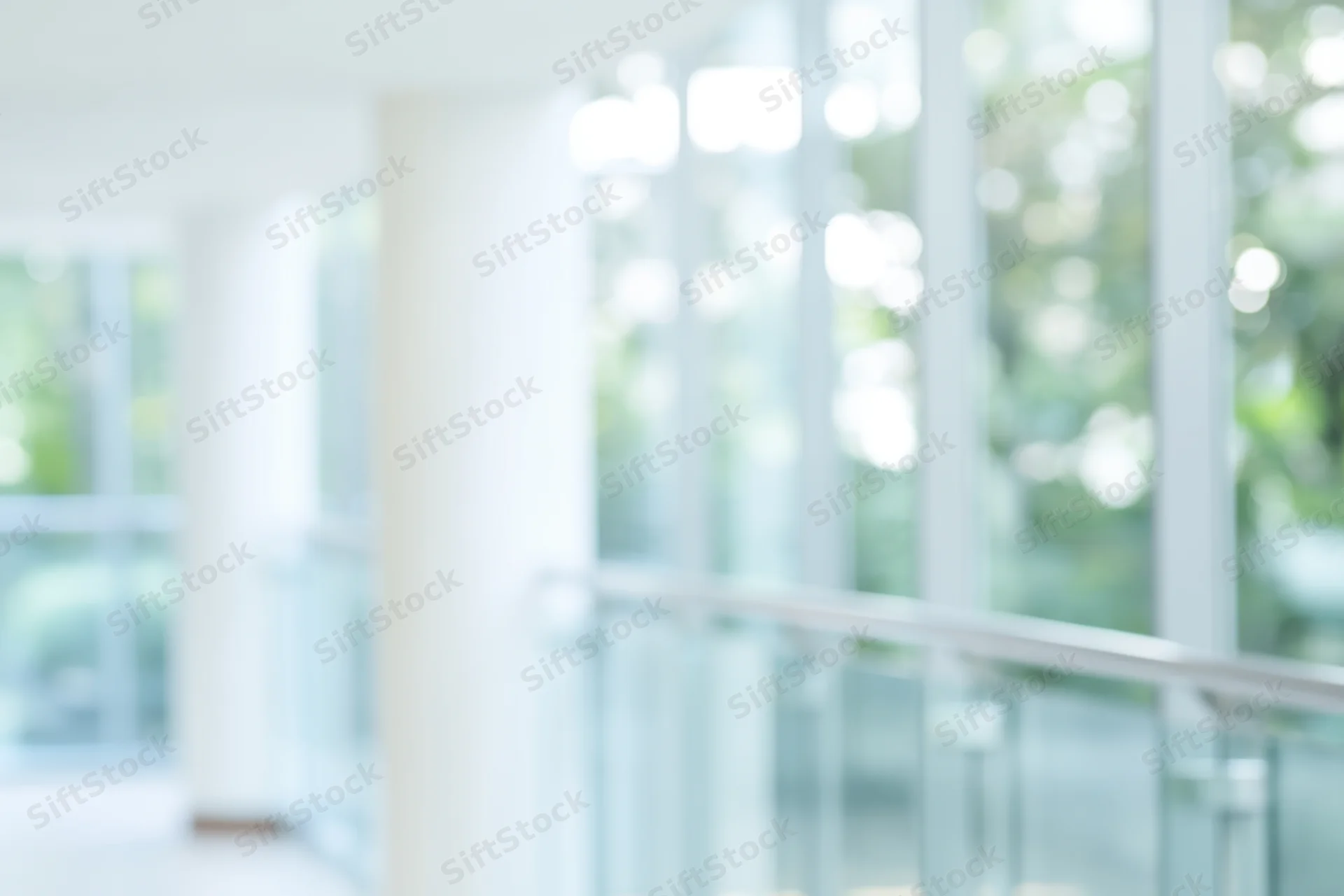 Blurred interior of a modern office building with glass walls and white columns