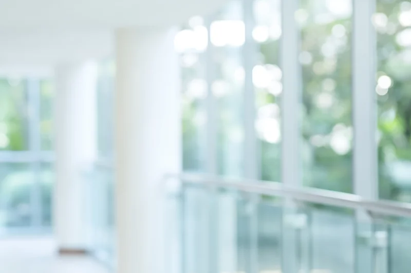 Blurred interior of a modern office building with glass walls and white columns