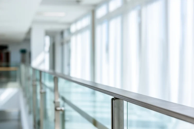 Glass railing along a bright modern office hallway with soft focus background