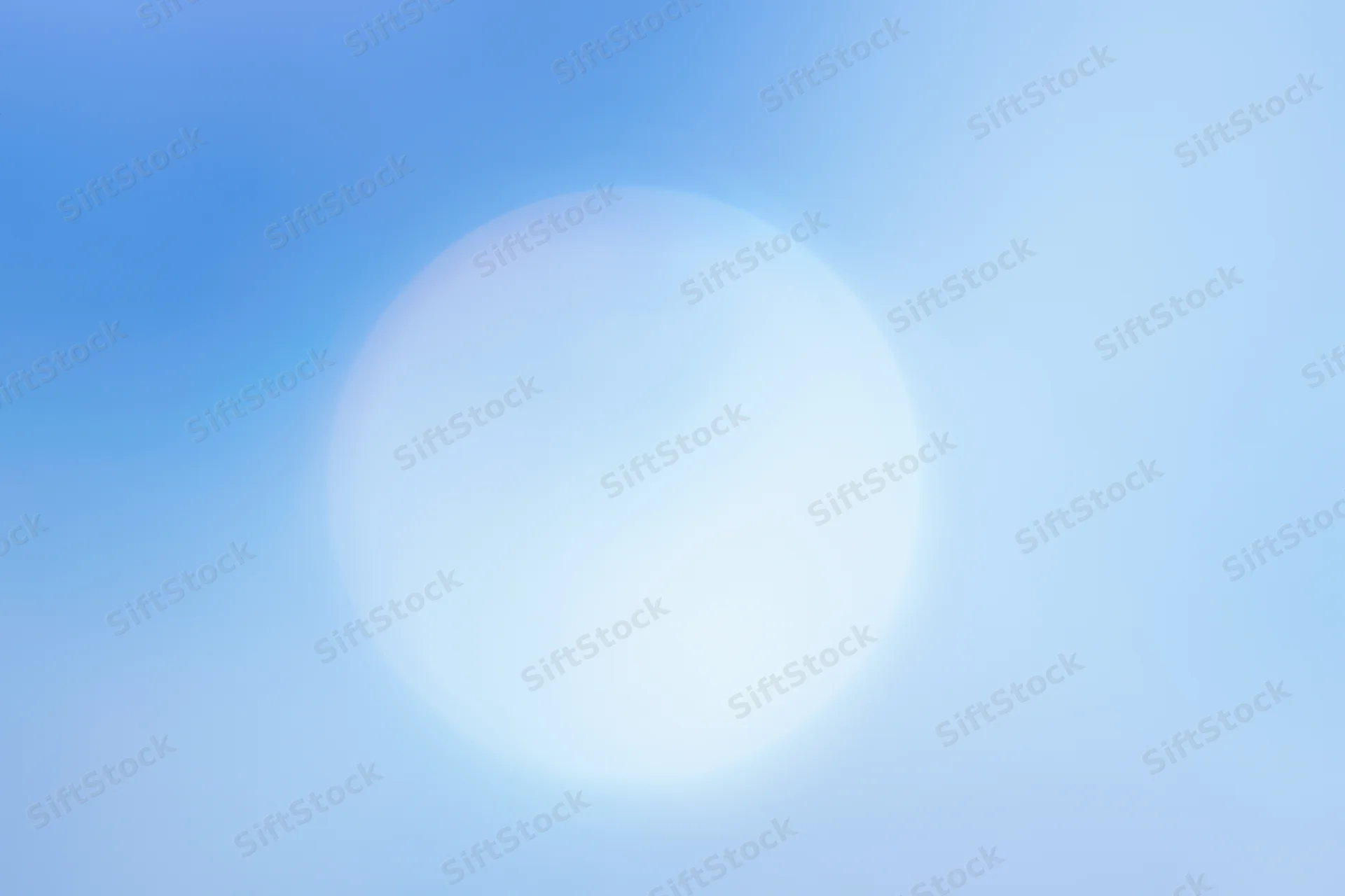 Bright circular sun glow in soft blue sky gradient