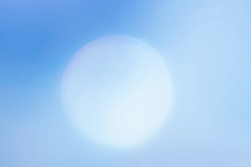 Bright circular sun glow in soft blue sky gradient