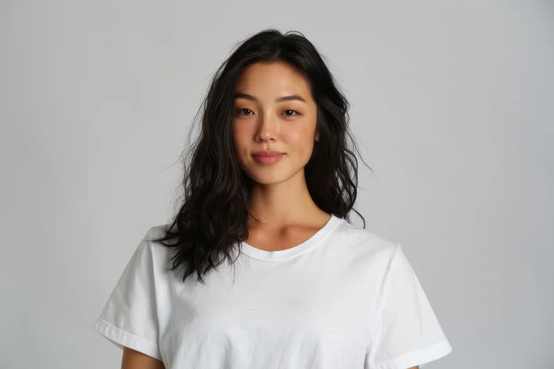 Young asian woman in plain white tshirt smiling at camera in studio setting