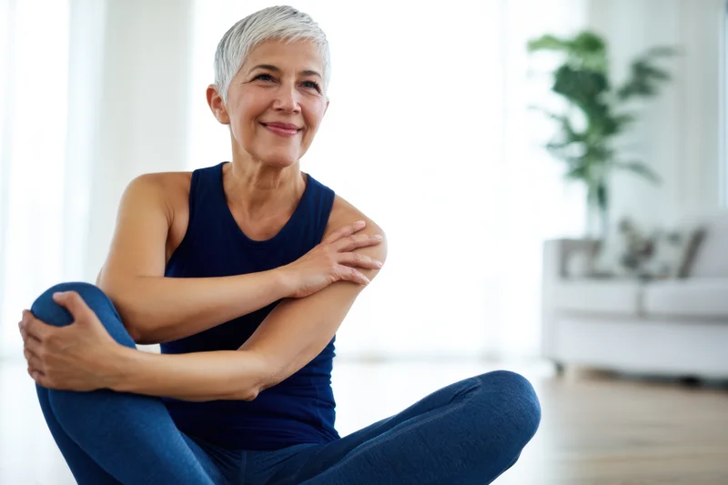Senior woman stretching in seated position at home