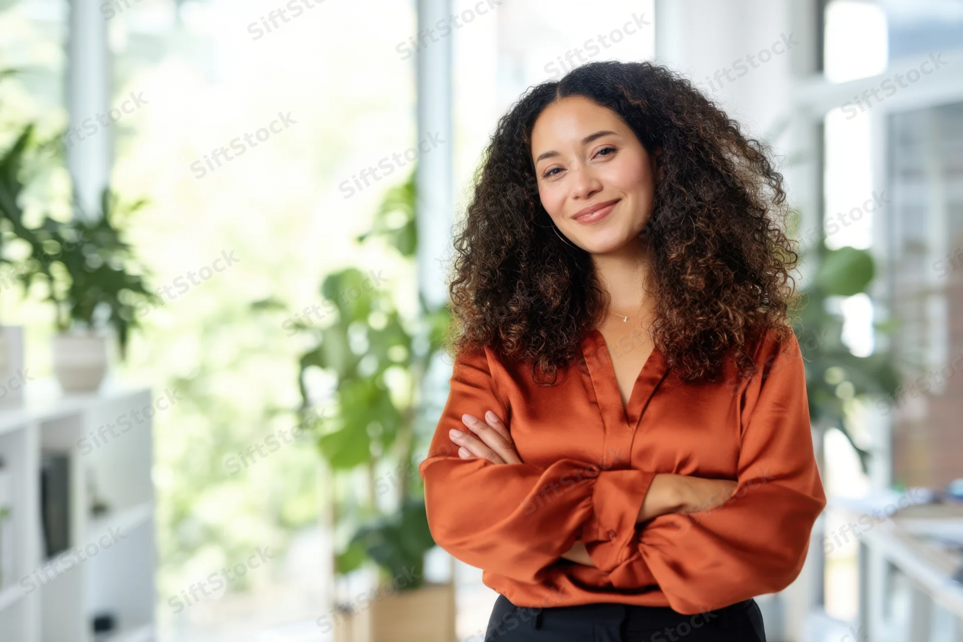 Confident woman with arms crossed smiling in modern office interior