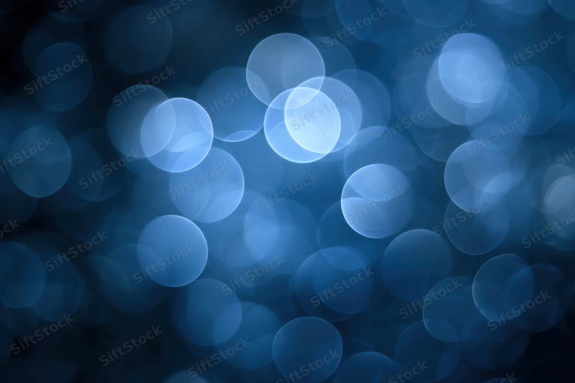 Soft glowing blue bokeh circles on a dark background with ambient light effect