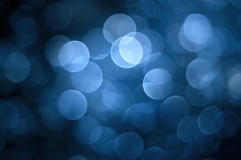 Soft glowing blue bokeh circles on a dark background with ambient light effect