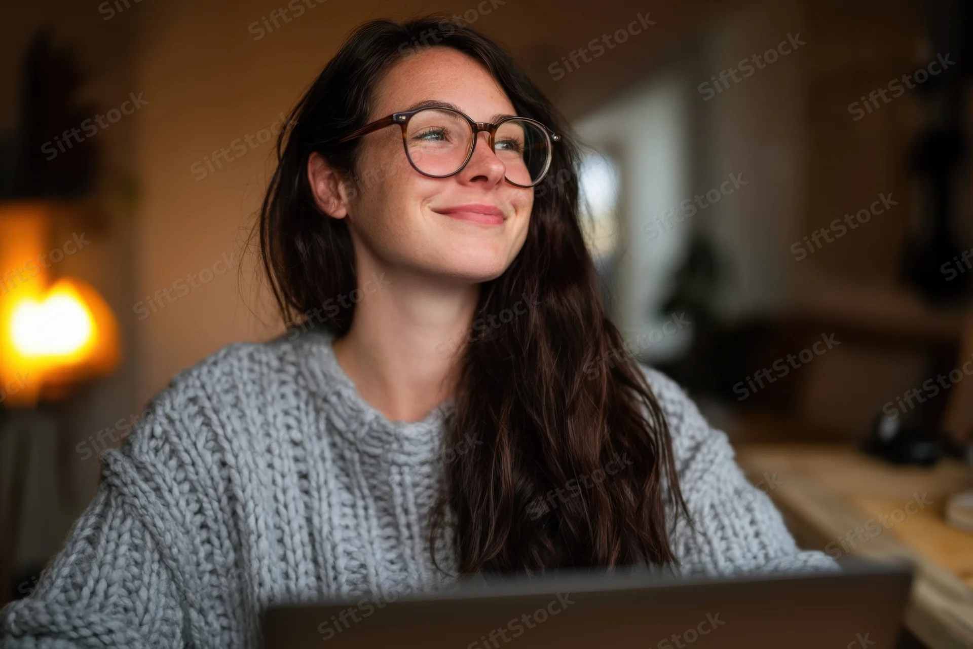 Woman smiling while working on laptop at home desk