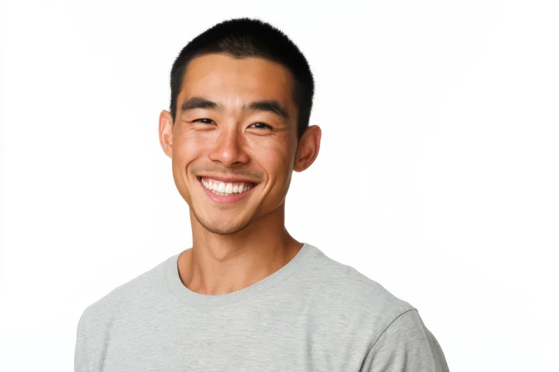 Young asian man smiling in a gray crew-neck t-shirt against a white background