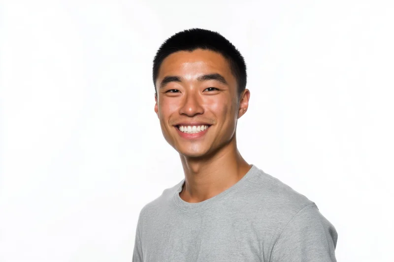 Young asian man smiling in a gray crewneck tshirt against white background