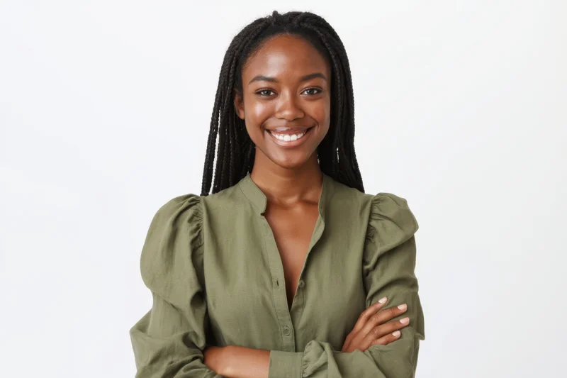 Young black woman smiling with arms crossed in green blouse against white background