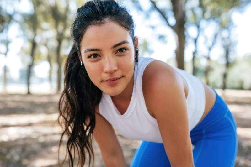 Fit woman bending forward during outdoor workout in park