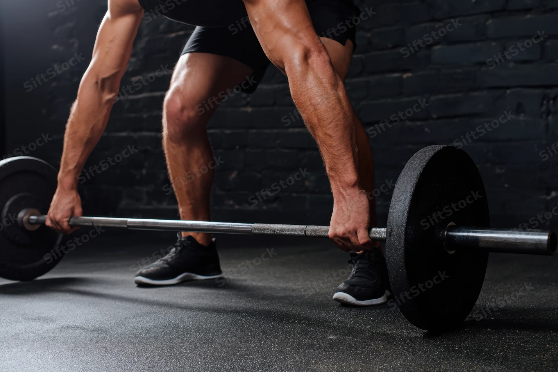 Man performing heavy barbell deadlift in dim gym
