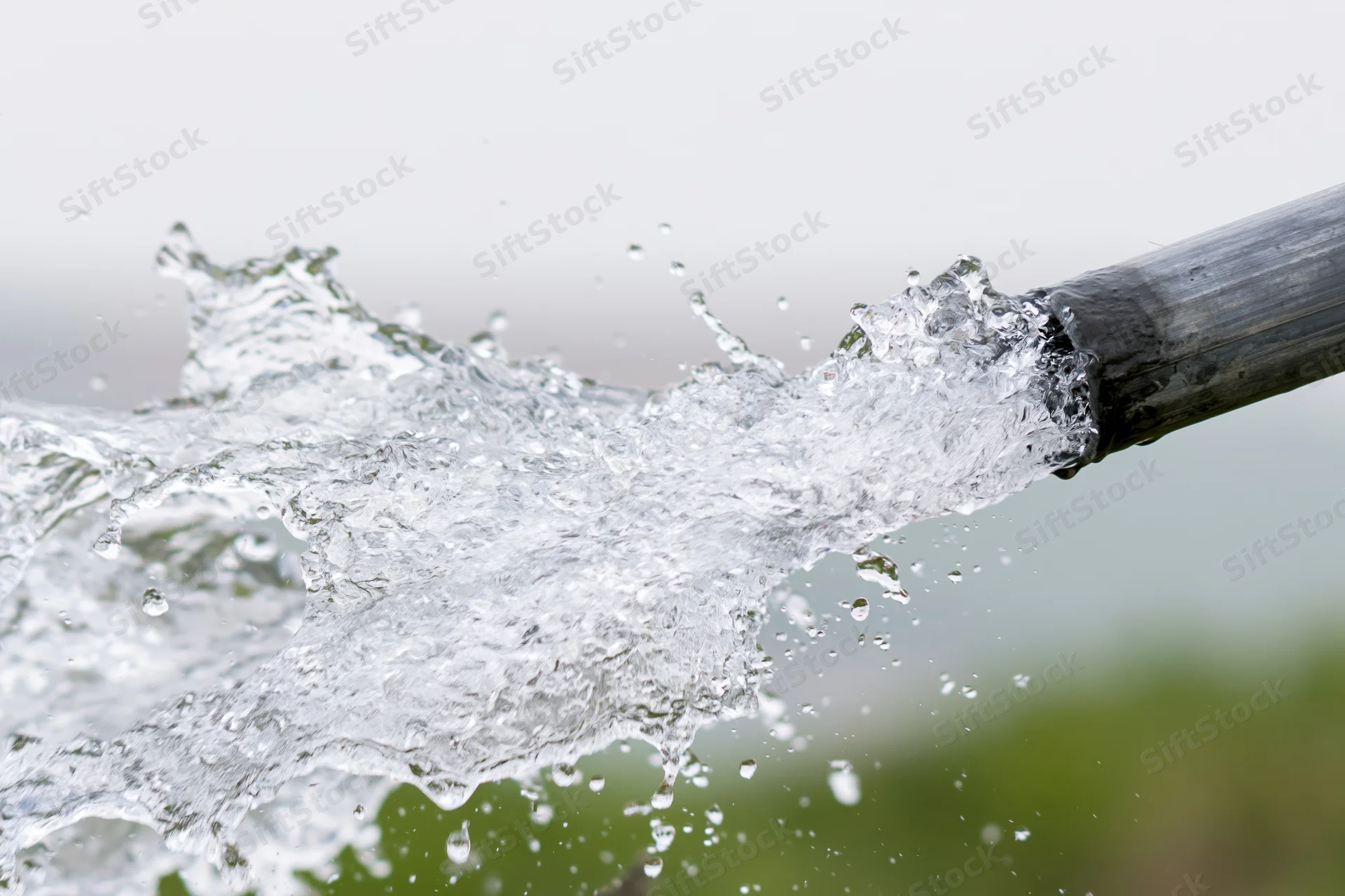 Clear water splashing forcefully from a bamboo pipe outdoors