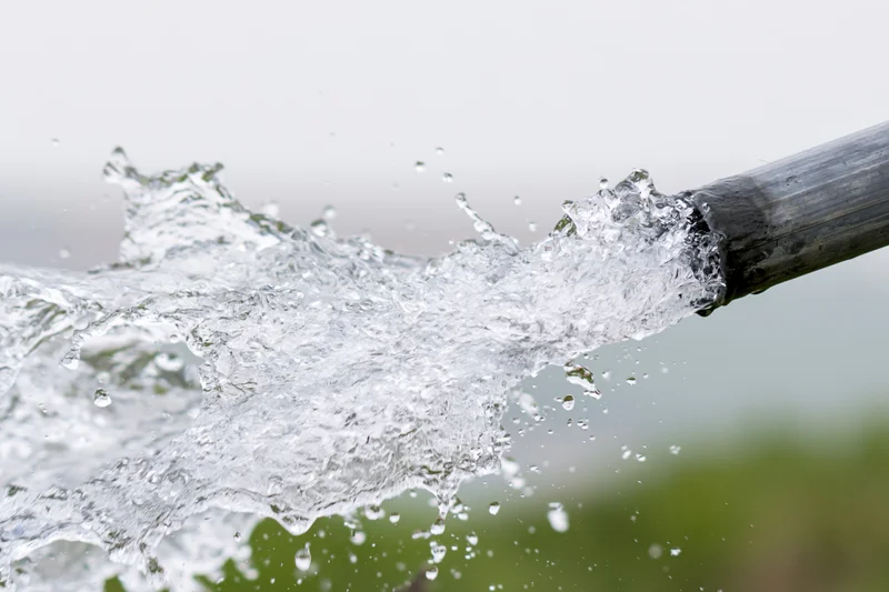 Clear water splashing forcefully from a bamboo pipe outdoors